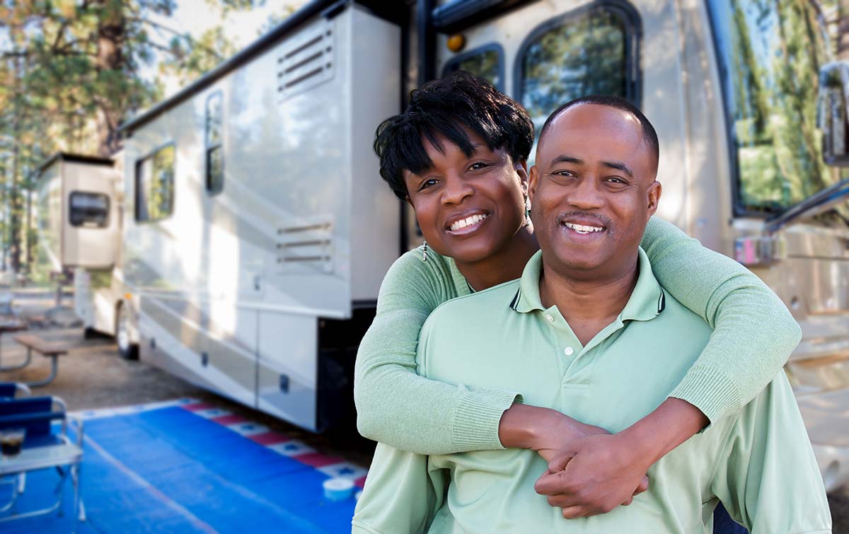 Happy couple in front of their recreation vehicle a campground after and RV inspection