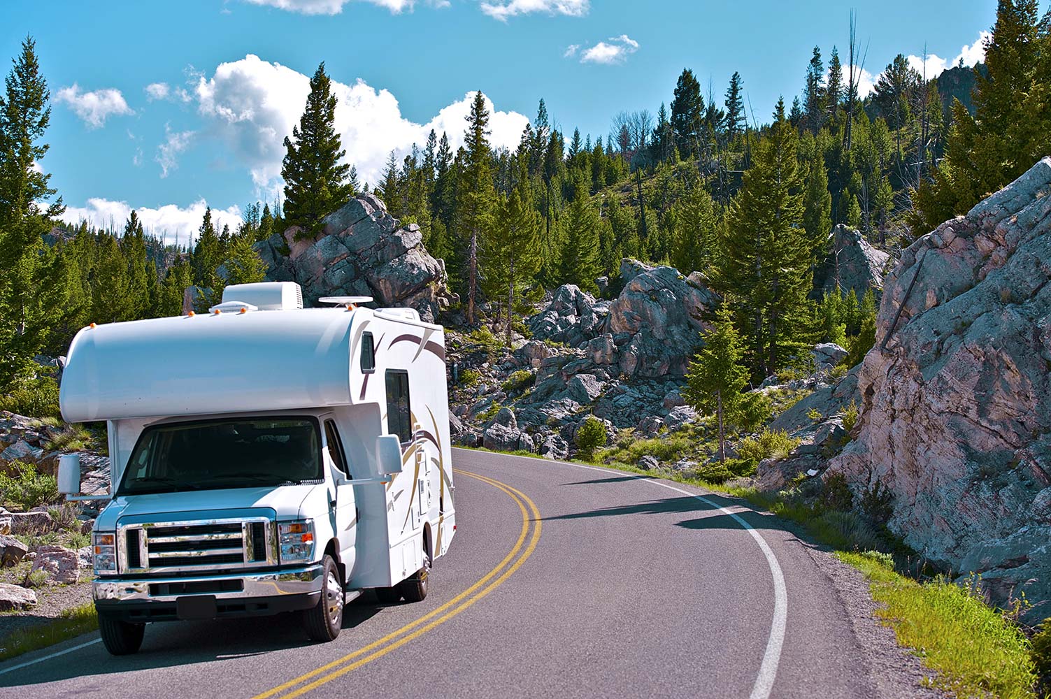 Recreation vehicle motorhome driving down a Rocky Mountain road after receiving rv inspection services