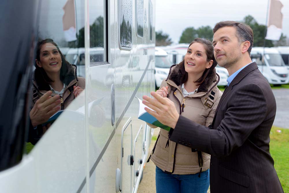 Salesman showing a woman a motorhome for sale after receiving thorough rv inspection services
